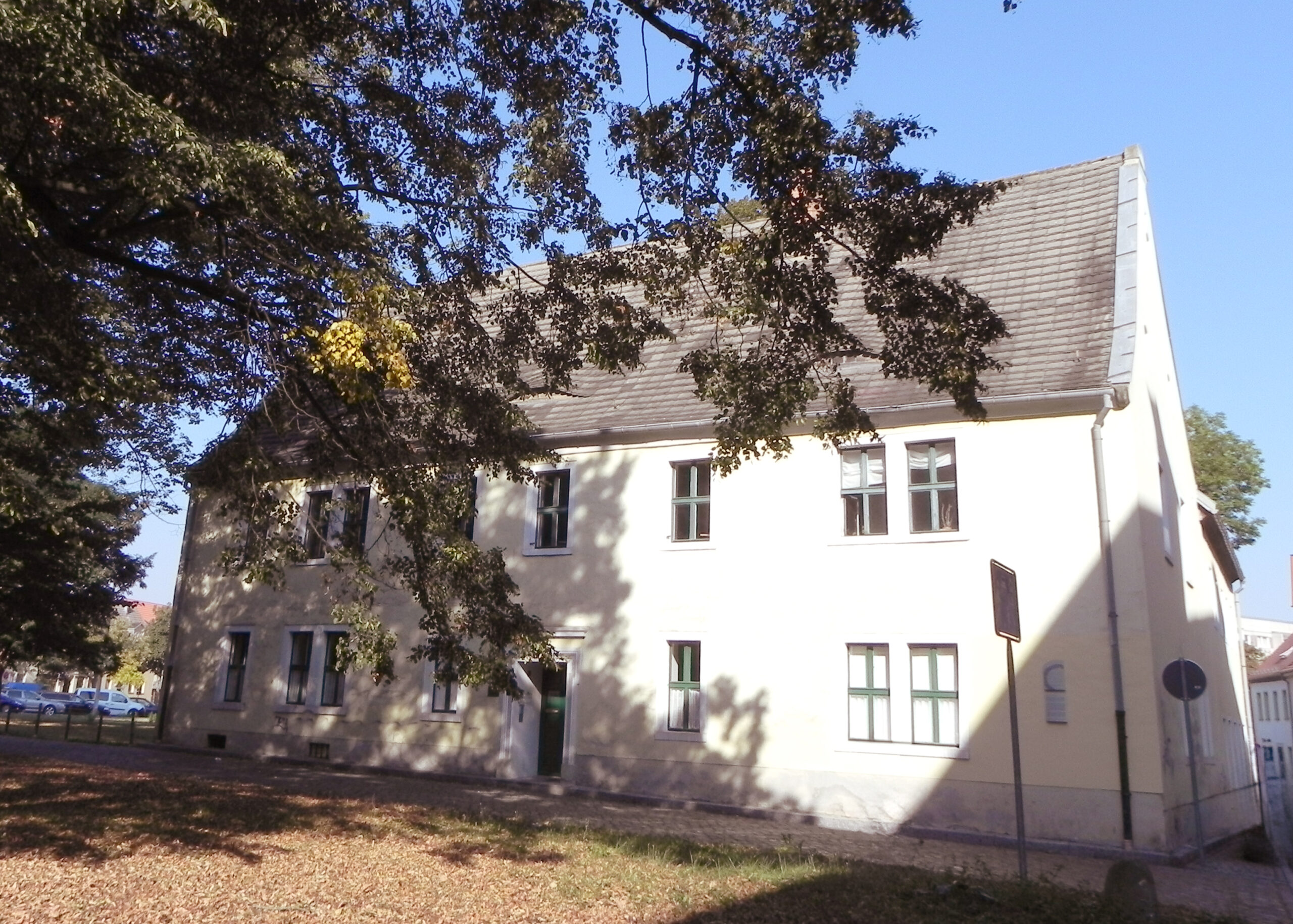 Gebäude der Tagesstätte in Bernburg mit einem großem Laubbaum im Vordergrund