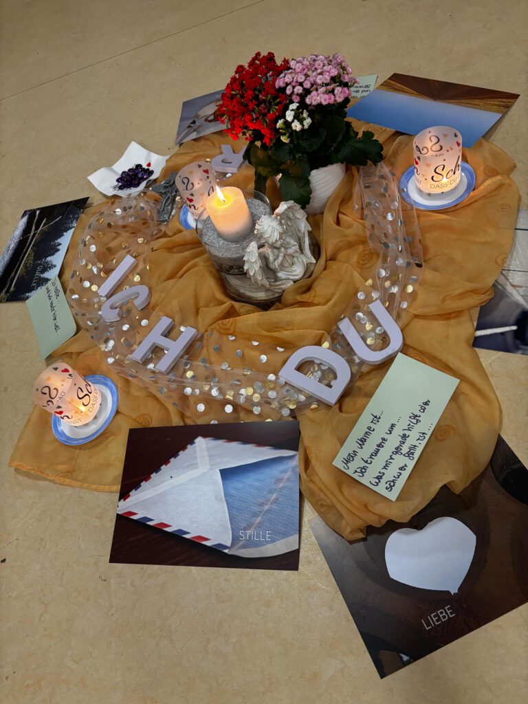 Dekorierter Boden mit Tuch, Blumen, Kerzen und Fotos welche an Verstorbene erinnern.